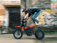 Person riding a red electric bike on a city street with blurred background