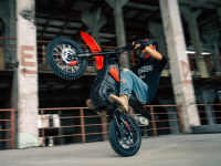 Person performing a wheelie on a motorcycle in an urban setting